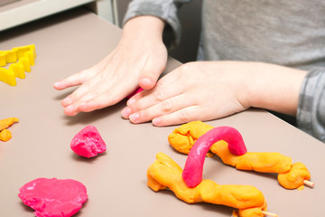 Obraz na płótnie Canvas Child's hands with colored plasticine. The child plays and creates figures from the game test. The boy is sculpting from clay.