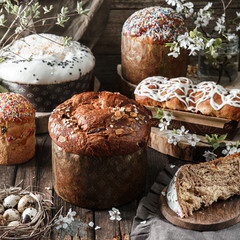 Set of different Easter cake or bread kulich with glaze, chocolate, candy and nuts on rustic wooden background with easter eggs and spring flowers. Happy Easter holiday