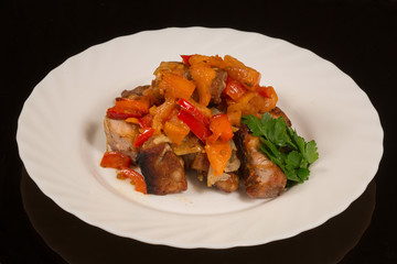 fried kebabs with vegetables on a white plate. against a black reflective surface