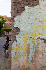 Muro en ruinas y niños con bicicleta jugando
