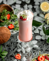 a glass of strawberry milkshake with whipped cream and strawberry on top