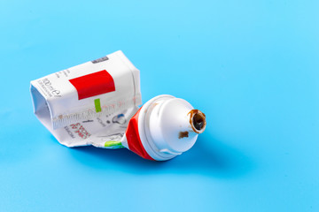 An empty tube of toothpaste on a blue background. The view from the top. There is a free space for the label on the background.