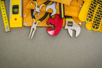 Plumbing tools in the bag and work gloves on gray desktop are used to replace or repair