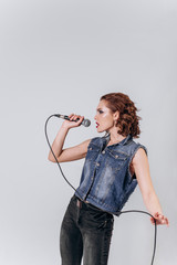 A beautiful girl with a microphone sings on an isolated white background