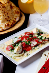 a platter of tomato salad with boiled eggs onion oil herbs and cream