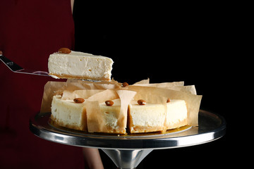 cheesecake with almond. confectioner hold dessert on pastry shovel. Classic dessert cheesecake isolated on black closeup