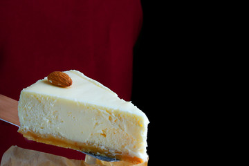 cheesecake closeup isolated on black. dessert with whole almond. confectioner hold dessert on pastry shovel.
