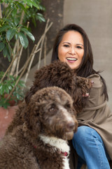 Mature Asian woman laughing and playing with her dog.
