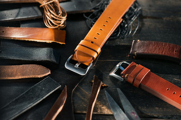 Handmade watch straps on wooden rustic surface. Different leather colour tones. Closeup.