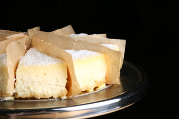 cheesecake decorating popcorn on black background. caramel dessert on stand and wooden table