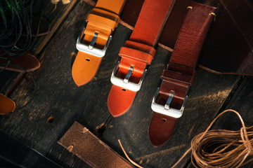 Handmade vintage brown leather watch straps with fashion steel buckle on rustic wooden black surface. Different leather colour tones.