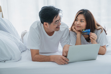 senior husband and wife are using laptop and credit card to buy products online.