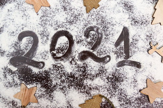 numbers 2021 paint handwritten on flour brown table and wooden flat christmas tree toys around