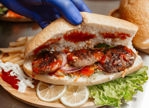 chef shows inside of the turkish kofte grilled meatballs garnished with ketchup