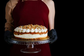 cake with walnut and cream cheese closeup. woman confectioner hold carrot layer dessert. gloved hands of a pastry chef