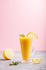 Glass of lemon drink on a gray and pink background. Side view