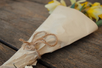 Natural Twine Bow on Handmade Rustic Vintage Daffodils Bouquet, close up view. Wooden background. 