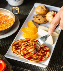 close up of man taking small pancake with strawberry syrup