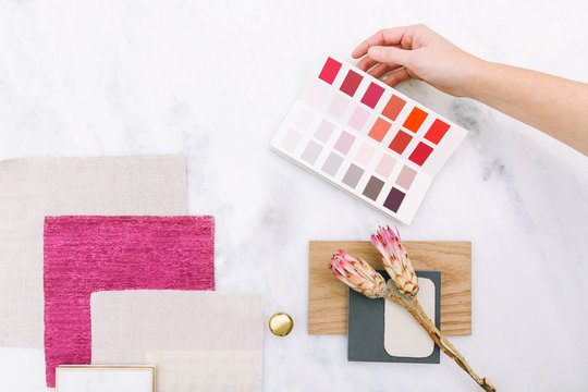 Interior Designer Selecting Paint Colors, Fabric Swatches, And Remodel Design Samples / Overhead Lay Down On White Marble Surface With Pink Color Story