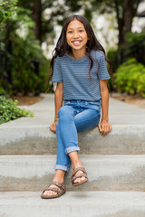 Portrait of a young Asian girl smiling outside.