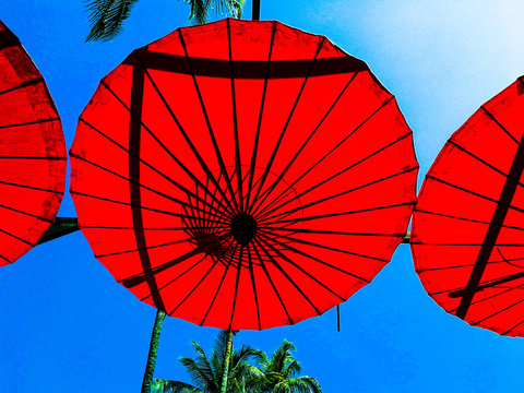 Low Angle View Of Red Umbrellas Against Blue Sky