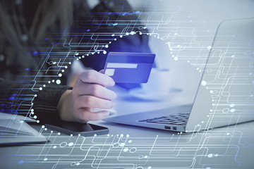 Double exposure of woman on-line shopping holding a credit card and data theme hologram drawing. E-commerce concept.