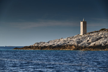 The lighthouse on the island in Croatia nearby Vis at sunset, a rocky coast, ladder to a beacon, a small cape