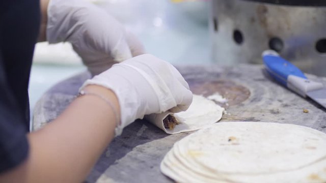 Chef cooking mexican burito at kitchen. tortilla with beef wraps meat. cooking mexican burrito. Waiter hands wrapping burrito filling in tortilla. Gourmet
