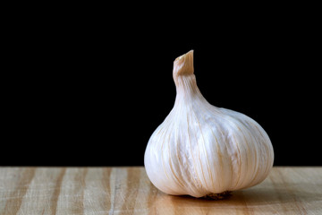 Garlic bulb on wooden table on black background..