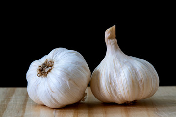 Garlic bulbs on wooden table on black background..