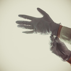 Nurse hands putting in purple medical latex gloves in the hospital before surgery against lights. Hand protection against viruses. Light mate background.