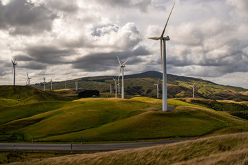 A  wind farm and turbines generating electricity on the top of the hills coexisting with the...