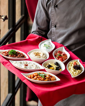waiter holds a tray with turkish meze side dishes