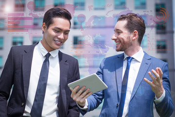 Joyful colleagues outdoors and virtual statistic graphics. Closeup of two young business men using tablet computer and walking with office building in background