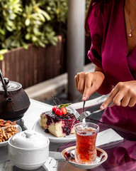 woman cutting a pie with cherry jam served with a glass of tea