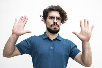 Concerned guy showing palms, hands, making surrender gesture. Handsome bearded young man in blue casual t-shirt posing isolated over white background. Calm down gesture concept