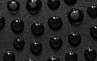 Water drops on black metal surface. 