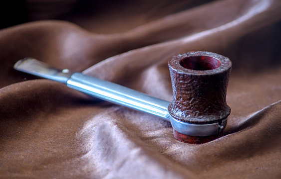 Aluminum smoking  pipe with a replaceable bowl on  a brown silk background