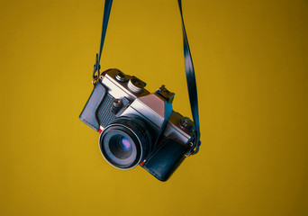 camara fotografica antigua sob re fondo amarillo mostaza