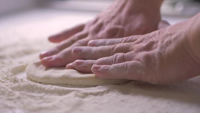Chef preparing dough for pizza on table