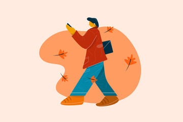 Man in red coat and blue trousers or jeans walking and listening to music with his mobile phone.
