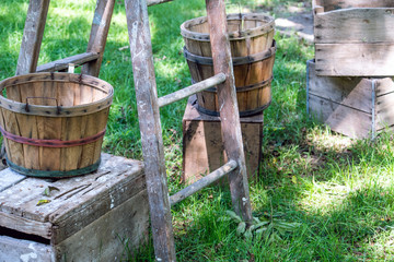 Baskets and crates rest next to a wood ladder in a  fruit orchard