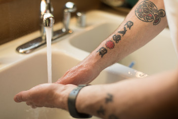 Close up of man washing hands in kitchen sink