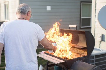 Mature man starting barbecue with lighter fluid