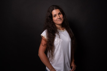 Beautiful caucasian girl looking at camera with charming smile. Black background