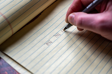 Caucasian hand using a pen to draw tally marks for counting