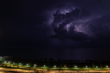 An intense thunderstorm cloud with blue or purple colors and lit up with numerous lightning strikes...