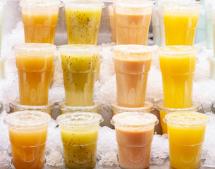 Smoothies made from various tropical fruits stand in a row on the market counter