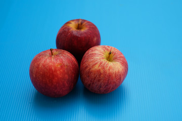 Three red apples on blue background