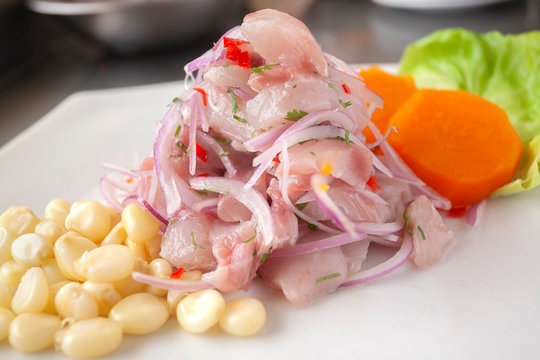 Peruvian seafood: fish cebiche with onion, chili, sweet corn and sweet potato served on a white plate